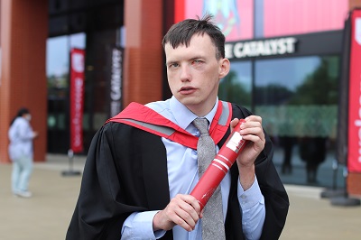 Jack Marshall in graduation robes holding a scroll