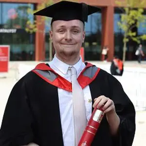 James Grist in his graduation robes holding a scroll