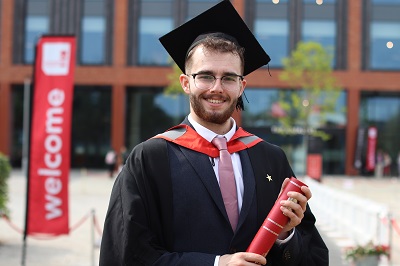Jared Darcy in his graduation robes holding a scroll