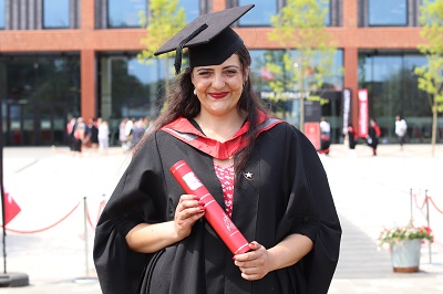 Jasmine Barton in her graduation robes holding a scroll