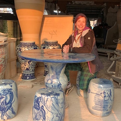 Smiling female kneeling at a decorated ceramic table
