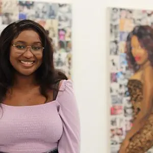Jioni Warner standing in front of her artwork