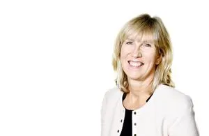 Smiling blonde woman in a pale jacket poses against a white background.