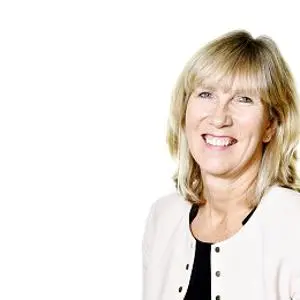 Smiling blonde woman in a pale jacket poses against a white background.