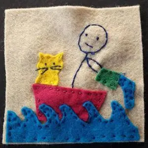 Felt embroidery of a stick figure and two cats in a red boat riding blue waves.