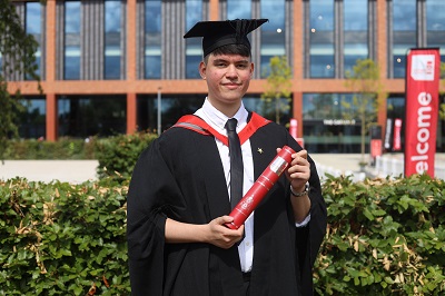 Lucas Ulitschnik in his graduation robes holding a scroll