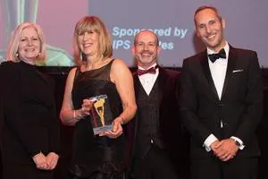 Four formally dressed adults pose with a trophy at a university awards ceremony.