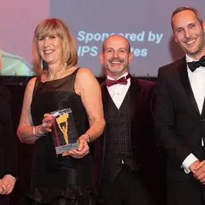 Four formally dressed adults pose with a trophy at a university awards ceremony.