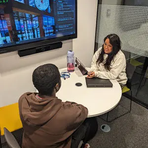 A student being interviewed at a table by a woman