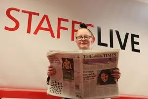 Woman holds an open newspaper beneath large red and black 'STAFFSLIVE' lettering.