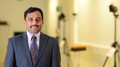 Man in a suit and patterned tie poses in a biomechanics laboratory.
