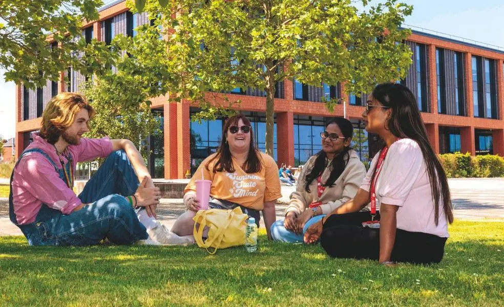A group of four students sat in front of the Catalyst building on a sunny day