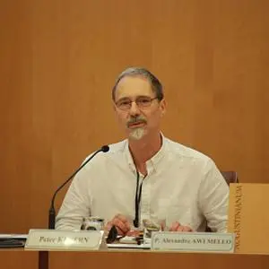 Older man in a white shirt speaks into a microphone at an international conference panel.