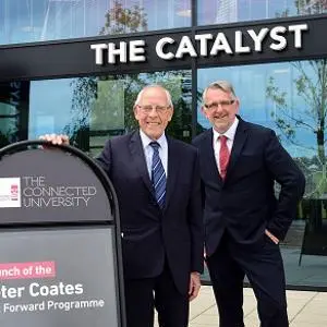 Two men stood by a sign outside The Catalyst building