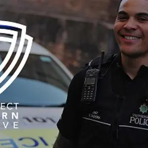 Smiling police officer beside a patrol car with the words 'Protect, Learn, Serve.'
