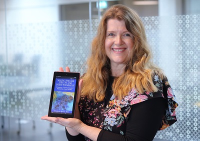 Professor Liz Boath pictured with a Kindle displaying her book