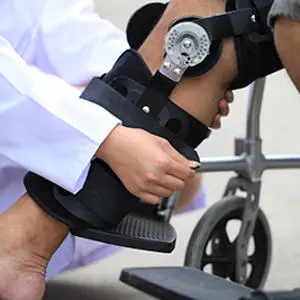 An orthotists fitting a brace on someone's leg