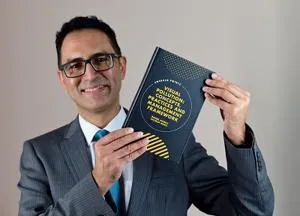 Head and shoulders pic of man holding a text book.