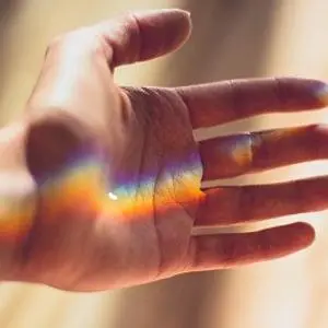 Open hand with a rainbow band of light across the palm and fingers.