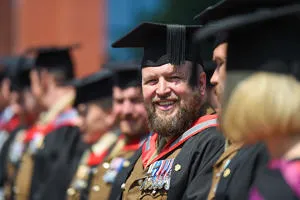 A smiling man in military uniform, wearing a graduation cap and gown