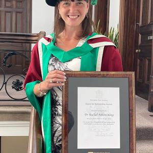 Dr Rachel Bolton-King holding her Outstanding Alumni Award certificate