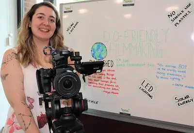 Film Production student Rebecca Head holding a camera in front of a whiteboard