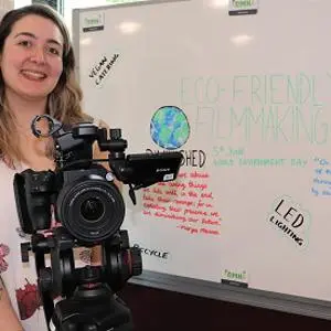 Film Production student Rebecca Head holding a camera in front of a whiteboard