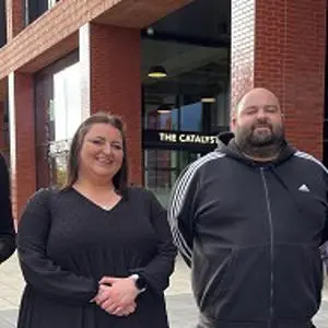 Four people stood outside the Catalyst building - two of which are holding awards