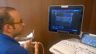 Man uses an ultrasound probe on a foot while viewing the scan on a monitor.