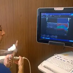 Man uses an ultrasound probe on a foot while viewing the scan on a monitor.