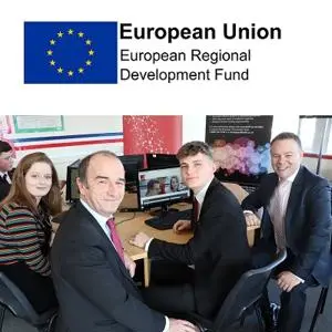 Adults and pupils gather around a computer beneath a European Union funding logo.