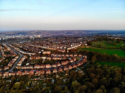 Aerial panorama of Sheffield showing dense housing, green hills and the city skyline.