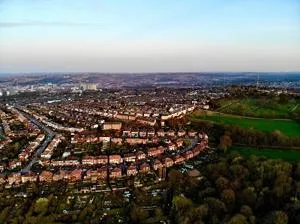 Aerial panorama of Sheffield showing dense housing, green hills and the city skyline.