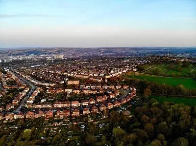 Aerial panorama of Sheffield showing dense housing, green hills and the city skyline.