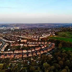 Aerial panorama of Sheffield showing dense housing, green hills and the city skyline.