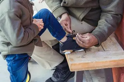 Adult tying up the shoelace of a small child