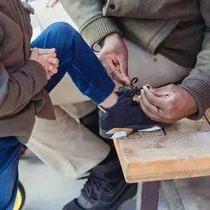 Adult tying up the shoelace of a small child
