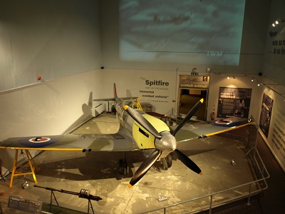 Spitfire aircraft displayed in a museum gallery with information panels around it.