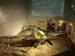 Spitfire aircraft displayed in a museum gallery with information panels around it.