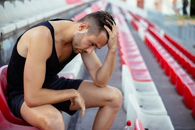 An athlete looking upset with his head in his hand