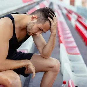 An athlete looking upset with his head in his hand
