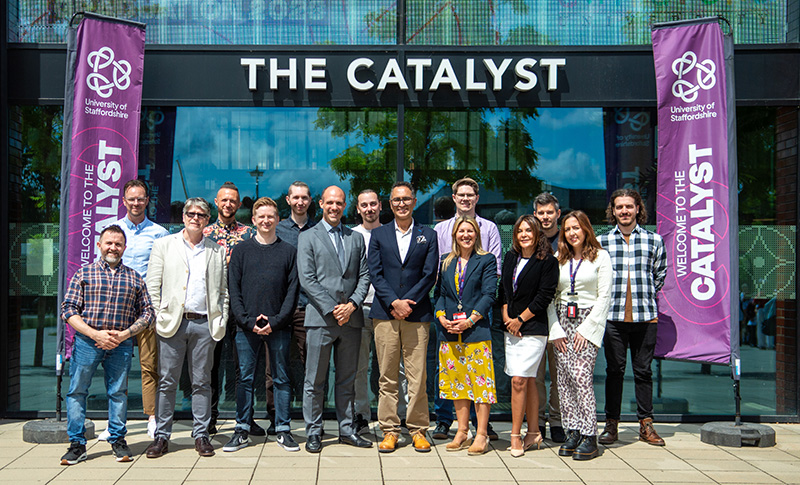 A large group of people in front of a building, underneath a sign that reads 'The Catalyst'
