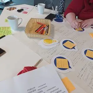 Table with sheets of paper pens and post it notes