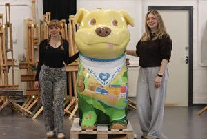 Students Grace Jones and Amy Watkins stood either side of a decorated Staffy Staffordshire Bull Terrier sculpture