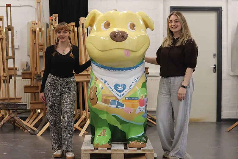 Students Grace Jones and Amy Watkins stood either side of a decorated Staffy Staffordshire Bull Terrier sculpture