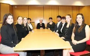 Law students and staff sit around a long conference table in a meeting room.