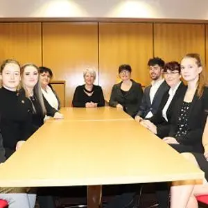 Law students and staff sit around a long conference table in a meeting room.
