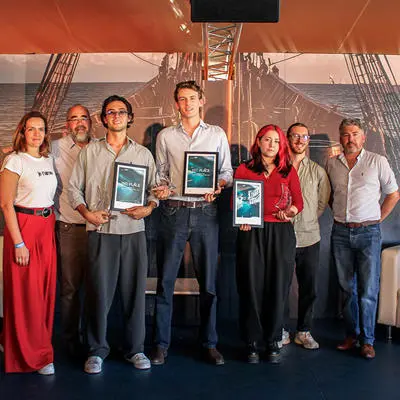 A group of seven people with three holding framed certificates