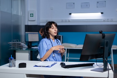 Picture of health worker sitting at desk in front of a pc