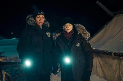 Kali Reis and Jodie Foster in True Detective, holding torches and wearing police uniforms